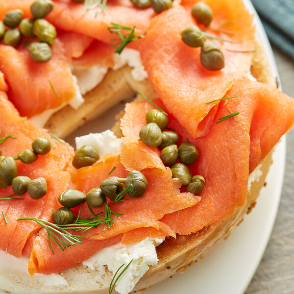 A bagel with smoked salmon, cream cheese, dill, and capers on a plate.