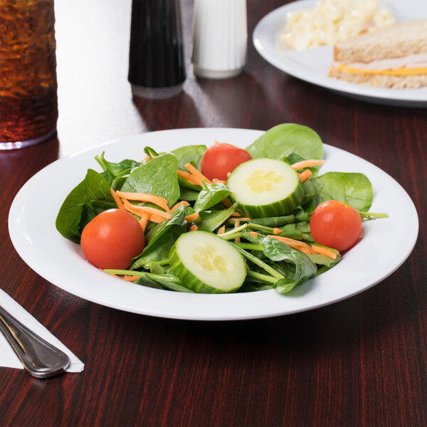 A Diamond White melamine bowl filled with a salad with tomatoes, cucumbers, and carrots.