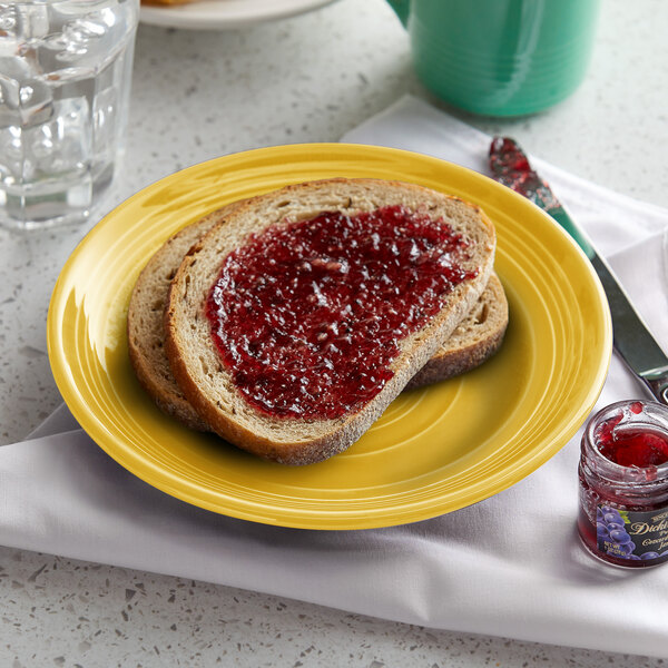 A Tuxton Concentrix saffron china plate with a piece of bread and jam on it.