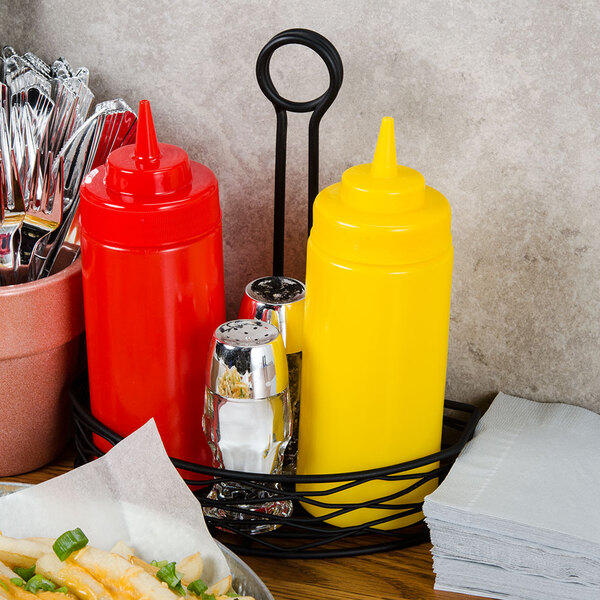 A Tablecraft black wire half condiment caddy holding condiments and silverware on a table.