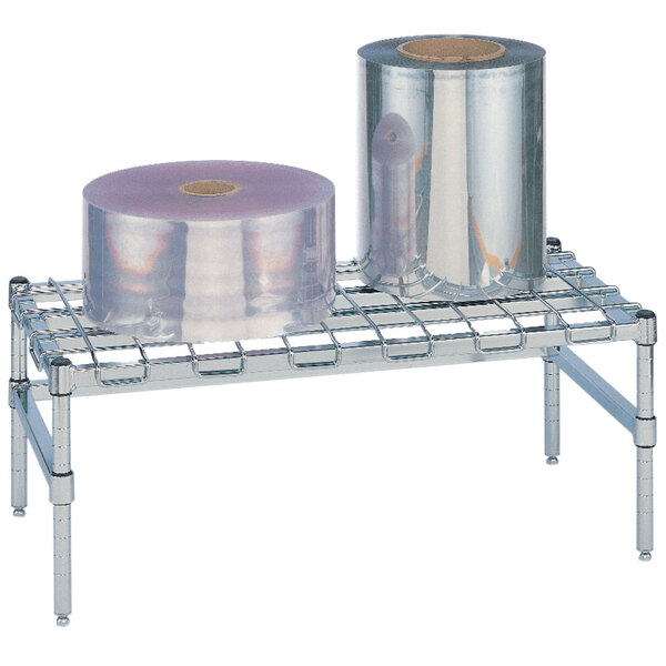 A Metro stainless steel dunnage rack with wire mat holding rolls of plastic wrap.