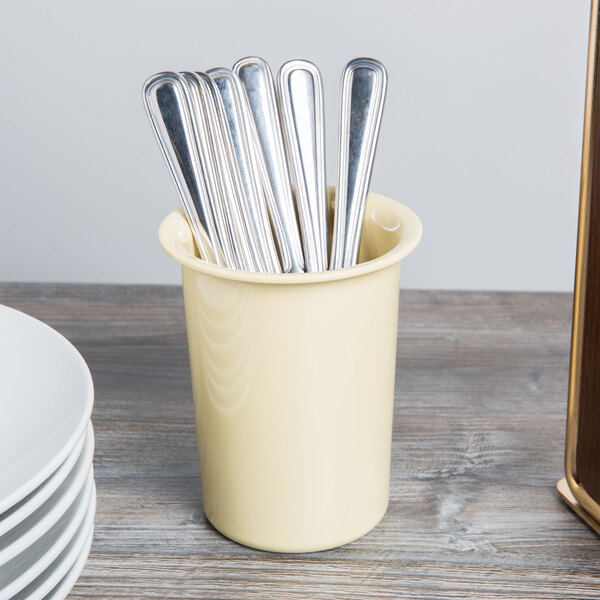 A yellow Cal-Mil flatware cylinder full of silverware.