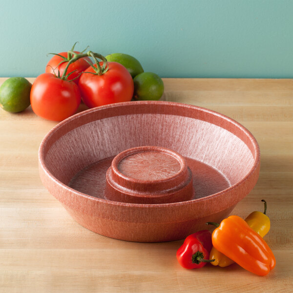 A bowl with tomatoes and peppers on a table.