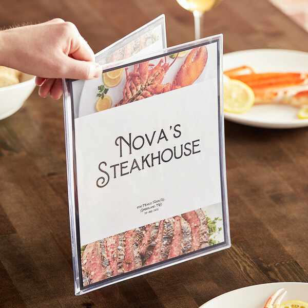 A person holding a menu at a table in a steakhouse.