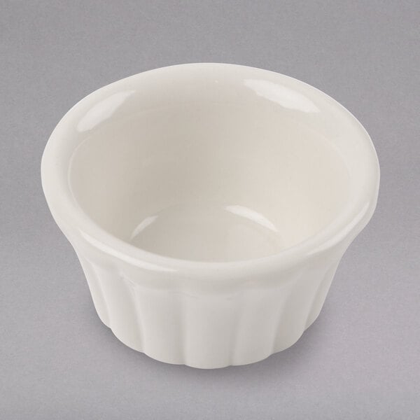 A close-up of a Hall China flared ramekin on a white surface with a shadow.