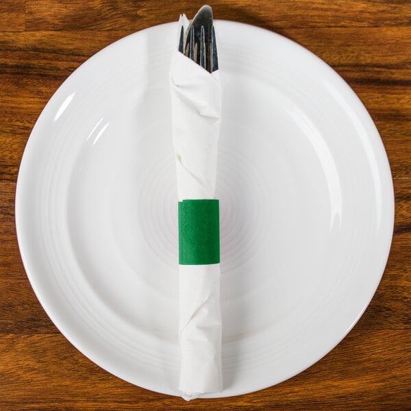 A white plate with a green customizable paper napkin band wrapped around a fork and knife.