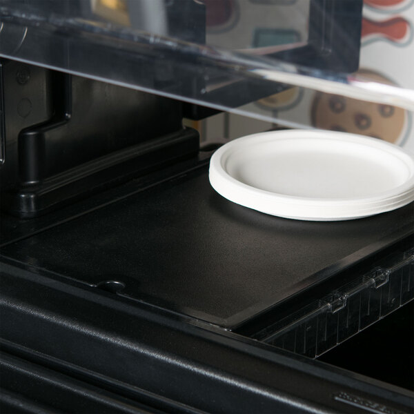 A white plate sitting on a black Cambro Versa Well cover.