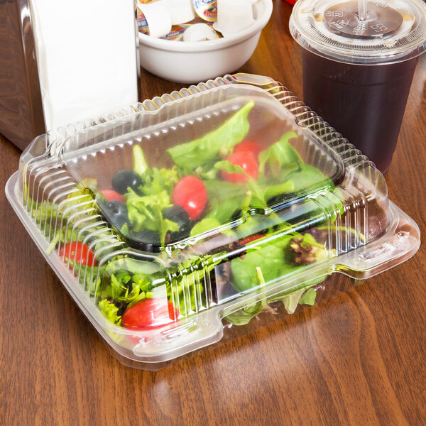 A salad in a Durable Packaging clear hinged plastic take out container on a table.