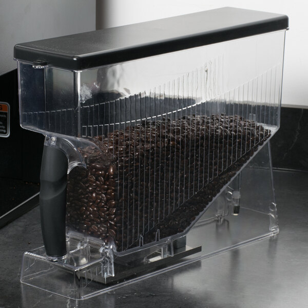 A Bunn MHG Smart Hopper with coffee beans in a clear plastic container on a counter.