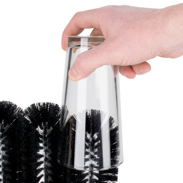 A hand holding a glass with a Carlisle Sparta black brush.