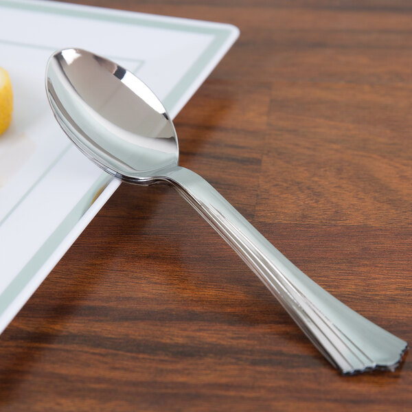 A WNA Comet Reflections stainless steel look heavy weight plastic spoon on a table.