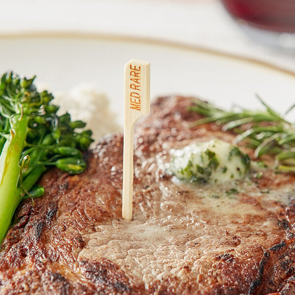 A Tablecraft bamboo meat marker with a steak and broccoli on a white plate.