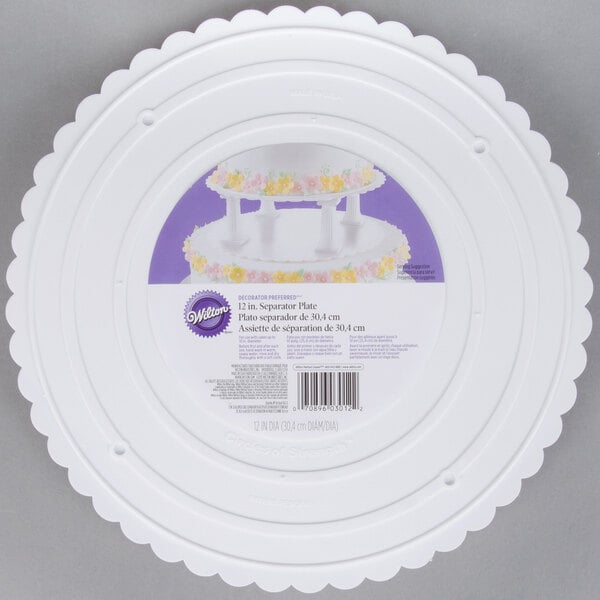 A white plastic Wilton cake plate with a scalloped edge.