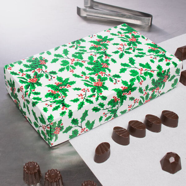 A 2-piece holly patterned candy box filled with chocolate candies.