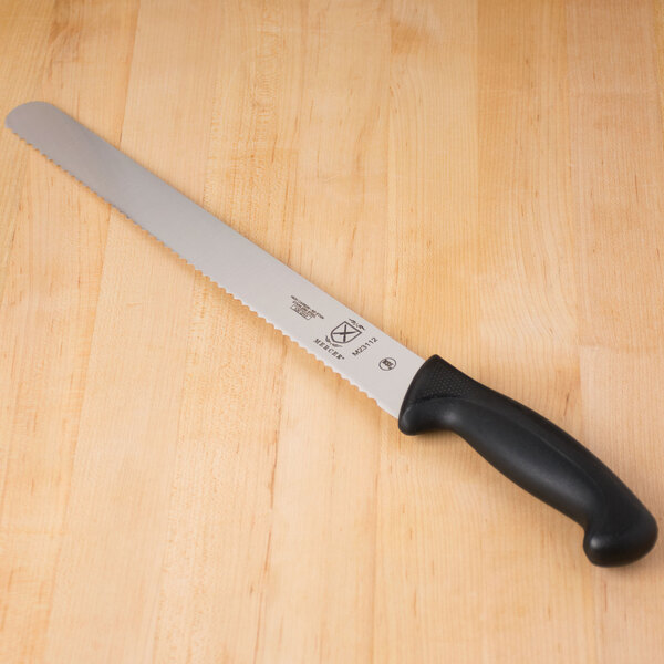 A Mercer Culinary Millennia 12" Serrated Edge Slicer Knife with a black handle on a table.