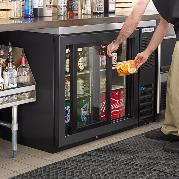 A man putting a drink into a Beverage-Air back bar refrigerator.