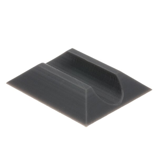 A grey plastic square with a curved hole in it.