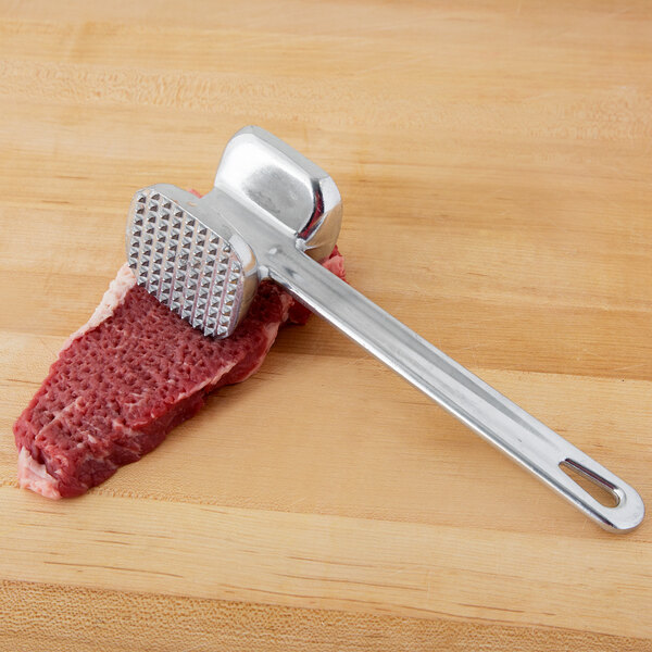 A Thunder Group meat tenderizer being used on a piece of meat.