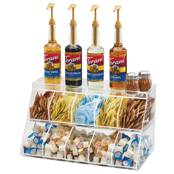 A Cal-Mil clear acrylic 10 bin condiment holder on a counter filled with condiments and condiment bottles.