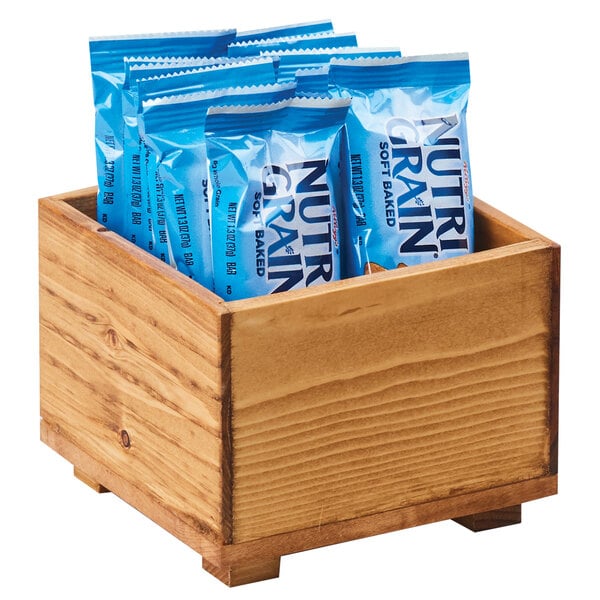 A Cal-Mil Madera wooden box filled with blue packages of food.