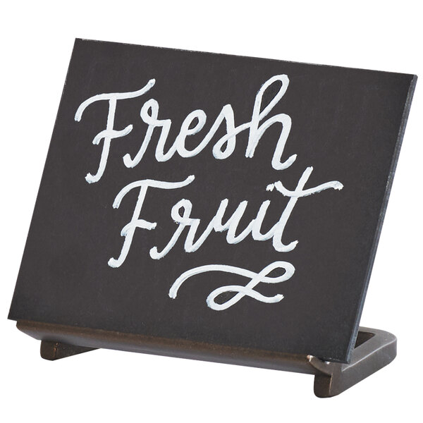 A Sierra chalkboard stand with white writing that says "Fresh Fruit" on a table.
