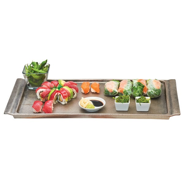 A Cal-Mil aluminum tray with sushi rolls, sushi, and sauce on it.