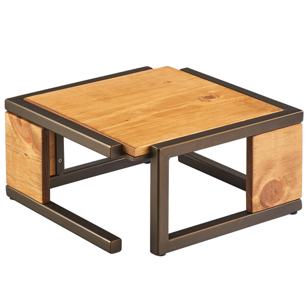 A wood and metal table with a Cal-Mil Sierra Bronze metal and rustic pine square riser on it.