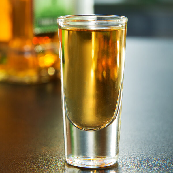 A Libbey tequila shooter glass filled with a brown liquid.