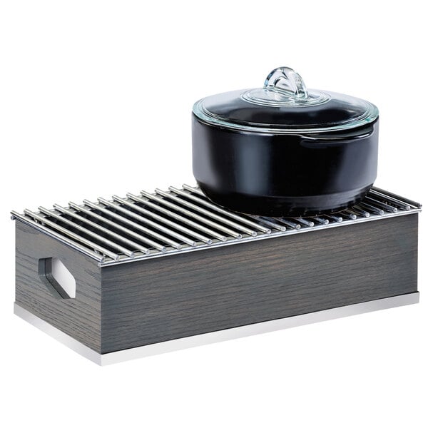 A black pot on a wooden tray with a metal grate inside.