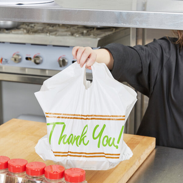 A woman holding a LK Packaging plastic "Thank You" take out bag.