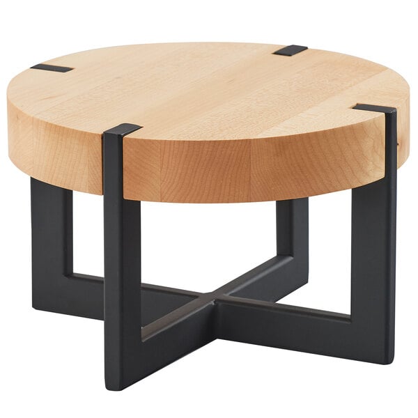 A round maple riser on a round wooden table with black metal legs.