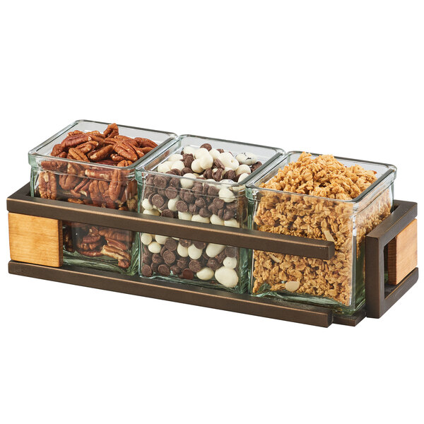 A Cal-Mil Sierra bronze metal organizer with 3 square glass jars holding different types of nuts.