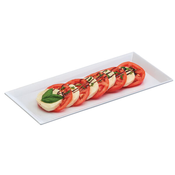 A rectangular white melamine tray with sliced tomatoes, mozzarella cheese, and basil.