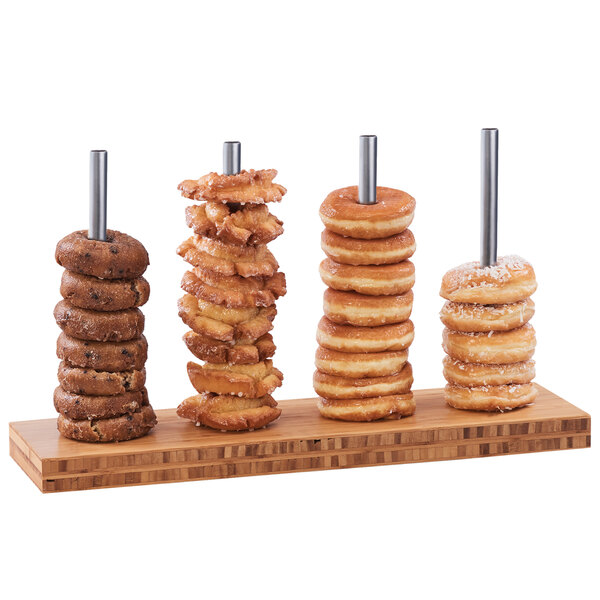A Cal-Mil bamboo display stand with doughnuts on metal pegs.