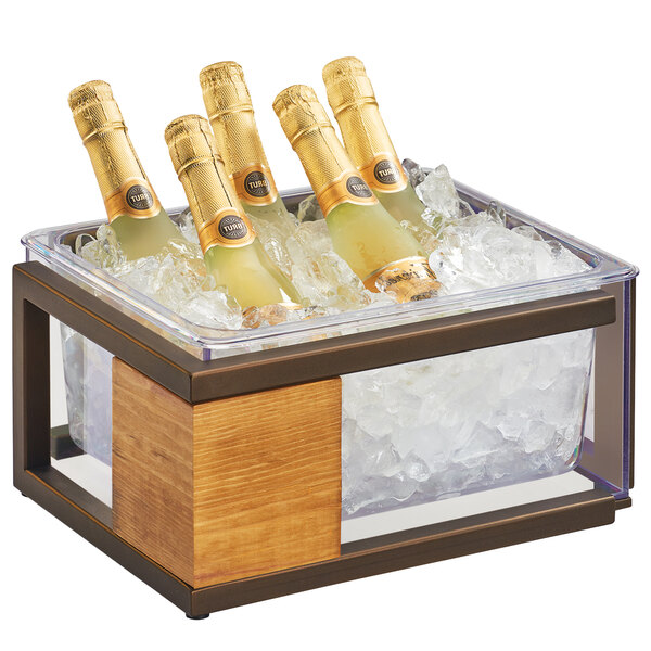A Cal-Mil Sierra bronze metal and rustic pine ice housing holding bottles of champagne on a table.