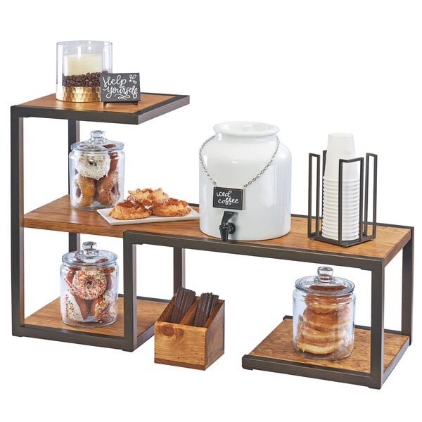 A Cal-Mil Sierra bronze metal and rustic pine riser display system on a table in a bakery display with food on it.