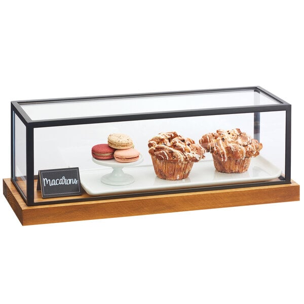 A glass Cal-Mil Madera presentation case with a muffin and macaroons inside.