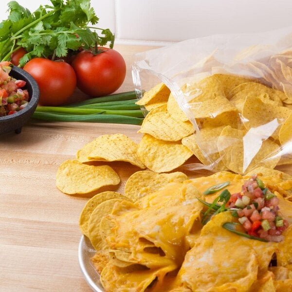 A plate of nachos with salsa and tomatoes using Mission yellow round corn tortilla chips.
