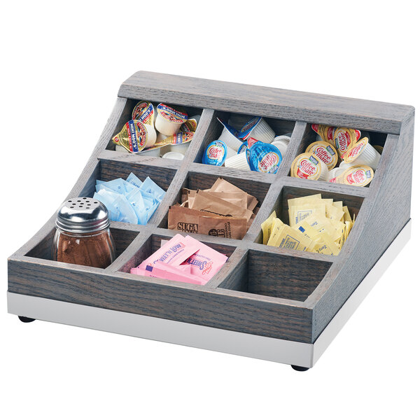 A Cal-Mil wooden condiment organizer with 9 compartments holding condiments.