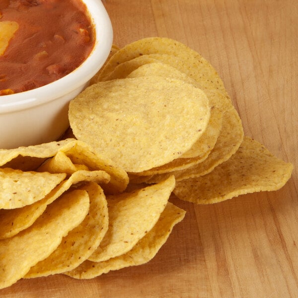 A bowl of chili and Mission yellow round nacho chips.