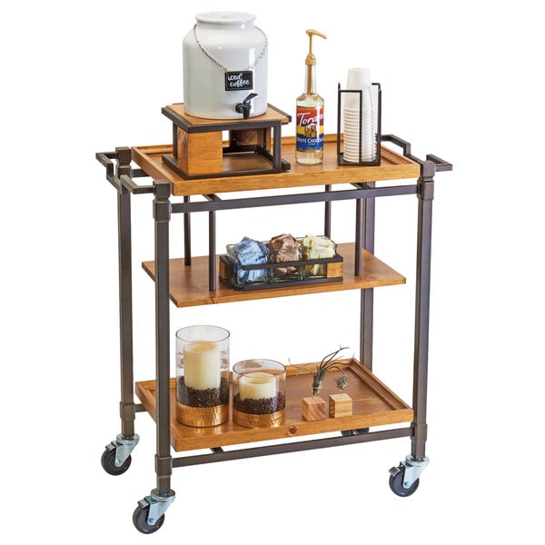 A Cal-Mil Sierra bronze metal and rustic pine serving cart with coffee and other items on it.