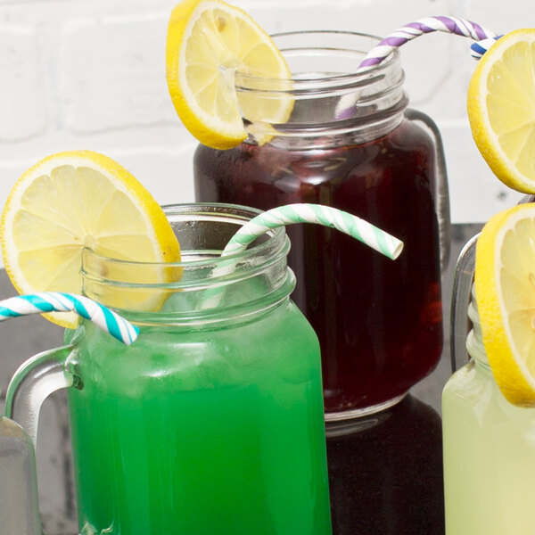 A group of drinks in mason jars with Creative Converting Fresh Mint Paper Straws and a lemon wedge.