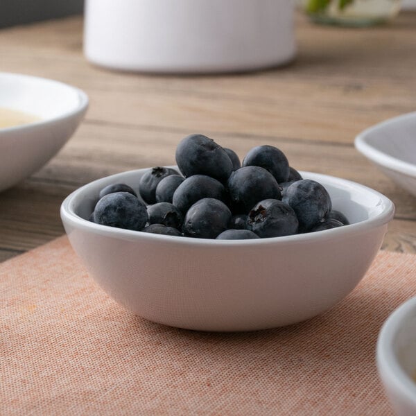 A white American Metalcraft melamine bowl with blueberries on a table.