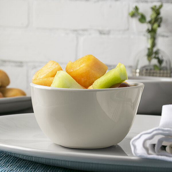 An American Metalcraft shadow melamine bouillon cup filled with fruit on a plate.