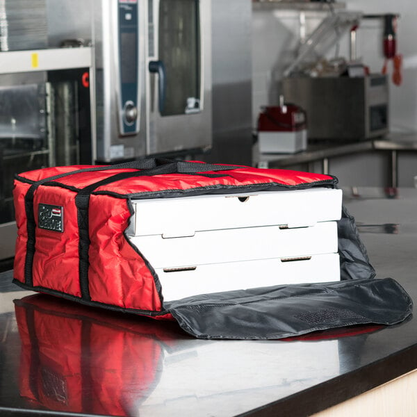 A red and black Rubbermaid insulated pizza delivery bag on a counter with white boxes inside.