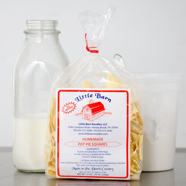 A bag of Little Barn Noodles pot pie squares next to a glass of milk.