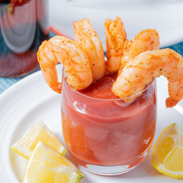 A shrimp cocktail with a lemon wedge on a plate.