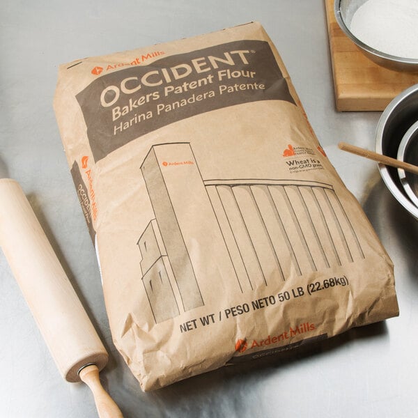 A bag of Ardent Mills Occident Bakers Short Patent flour next to a rolling pin on a counter.