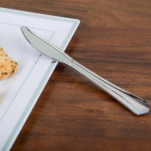 A WNA Comet Reflections stainless steel look plastic knife on a plate.