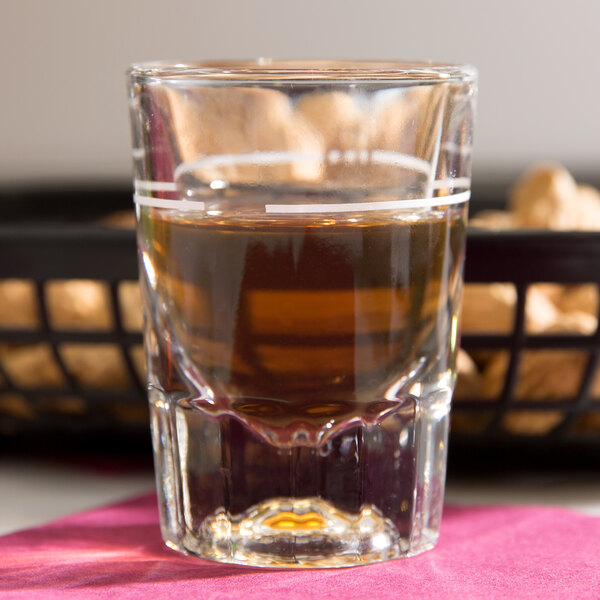 A Libbey fluted shot glass filled with liquid on a napkin.